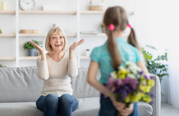 Back view of girl greeting woman with flowers