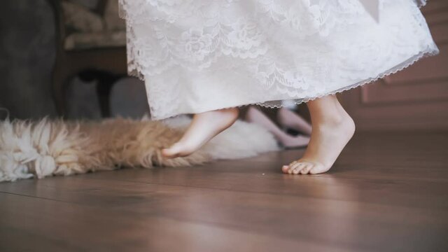 cute little girl. kid dance. close-up. little Princess, in a snow-white lace dress, dances, whirls, barefoot in the room.