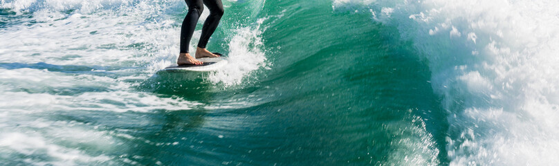 Fototapeta premium Wakeboarding. Close up of woman in wetsuit learning to wakesurfing behind wakeboard boat. Female surfing motorboat waves on river. Banner image with copy space