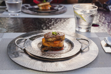 Foie gras on silver plate with sauce.