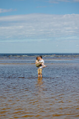 a man and a woman in love embrace and walk in nature. a man plays guitar or ukulele for his bride or wife and has fun. beautiful and young European man and woman on a romantic walk in nature enjoy