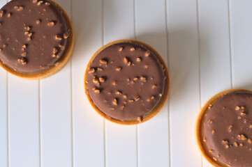 Round sweet delicious tarts covered with milk chocolate with nut pieces