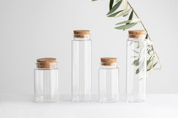Small glass jars on white background with olive branch and shadow
