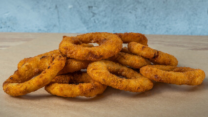 A close-up image for the bar menu. Juicy crispy onion rings lie on a crafting background with parsley leaves.