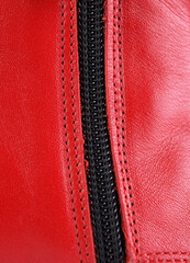 Zipper metal lock on a red leather boot close-up.