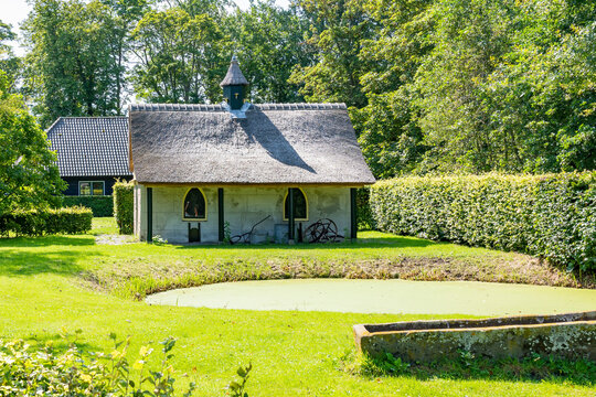 A small thatched outbuilding next to a pond in a park in Lisse, the Netherlands