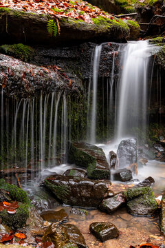 Creek Cascade &ldquo;Heslacher Wasserf&auml;lle&ldquo; with moss, wet rocks and brown foliage on a winter day in a forest near Stuttgart Vaihingen Germany with longtime exposure and blurred waterfalls, close up.