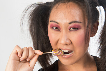 Korean woman with pigtails eating a lollipop