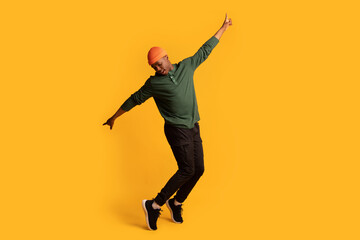 Fototapeta na wymiar Cheerful young african american man standing on tiptoes over yellow background