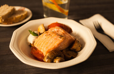 steamed salmon fillet on a pillow of fried mushrooms and tomatoes in a white bowl