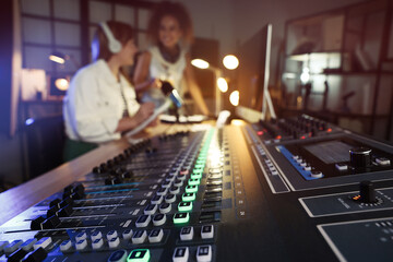 Women working in modern radio studio, focus on professional mixing console
