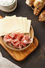 Savoury breakfast ingredients: brown lye bread sticks garnished with oats , pork slices prosciutto,...