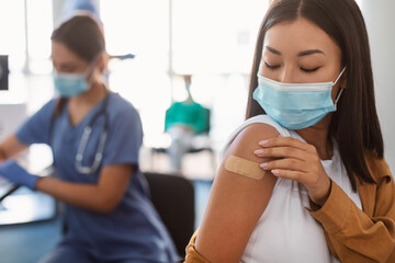 Happy Lady Showing Vaccinated Arm With Adhesive Bandage In Clinic