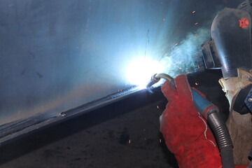 Obraz premium Skillful metal worker working with arc welding machine in factory while wearing safety equipment. Metalwork manufacturing and construction maintenance service by manual skill labor concept.