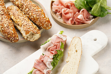 Long sandwich in brown lye bread sticks garnished with oats , pork slices prosciutto, hard cheese...