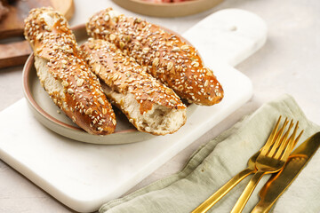 Savoury breakfast ingredients: brown lye bread sticks garnished with oats and seeds, pork slices prosciutto, hard cheese gouda on marble board