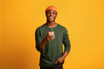 Online Communication. Cheerful young black man holding smartphone and smiling at camera