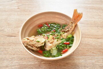 spicy boiled fried red bass fish and  herb in tom yum soup on bowl