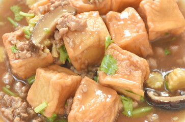 deep fried fish tofu with chop pork topping slice mushroom in sweet and sour gravy sauce on plate