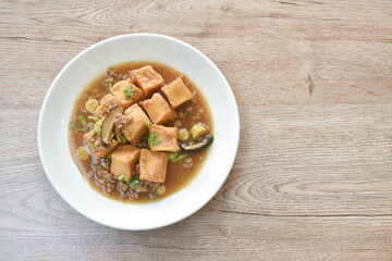 deep fried fish tofu with chop pork topping slice mushroom in sweet and sour gravy sauce on plate