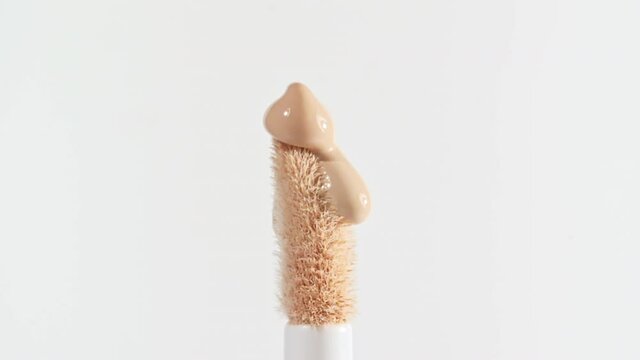 Make-up liquid beige foundation pouring on makeup brush, closeup. Cosmetic Dripping bb Cream on white background. Macro Shot. Beautiful Makeup concept. High quality 4k footage