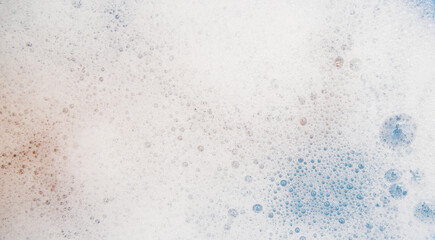 Abstract background texture of white soap foam. Shampoo foam with bubbles on a blue background.