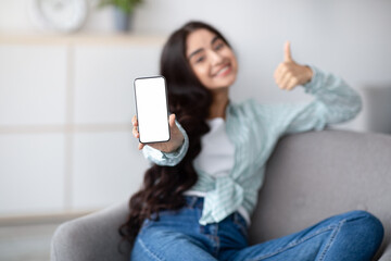Awesome mobile app. Indian lady presenting smartphone with white blank screen and showing thumb up at home, mockup