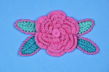 A decorative arrangement of handmade flowers and leaves on a blue crepe paper background.
