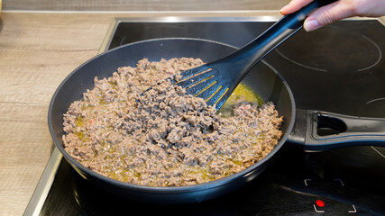 Chef frying minced meat in a pan. close up