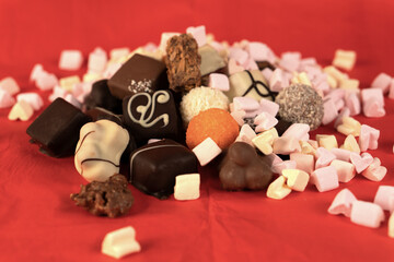 Chocolate candies and marshmallow on a red background. Group of different sweets. Square dessert. Valentine's day gift. Diathesis risk.