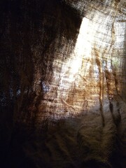 Abstract background. Light passes through the rough fabric. Sacking, rays of light, gloomy mood. Image for prints, poster and illustrations.