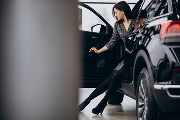 Fototapeta na wymiar Young woman in a car showroom choosing a car
