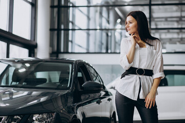 Fototapeta na wymiar Young woman in a car showroom choosing a car