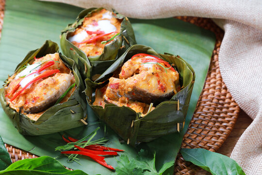 Traditional Steamed snakehead fish with curry paste and tahitian noni leaf inside. Red chili and kaffir lime leaves and coconut milk on top. (Homok) Thai foods concept.
