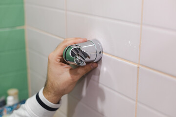 Man hand attaching and installing shower head holder with crosshead screwdriver to tiled wall in...