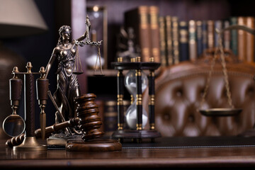 Fototapeta na wymiar Judge office. Gavel, scale, Themis sculpture on the desk. Law books in the bookshelf.