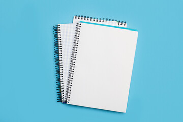 Cuaderno escolar sobre un fondo azul liso y aislado. Vista superior y de cerca. Copy space.. Bloc de notas en espiral sobre una mesa.