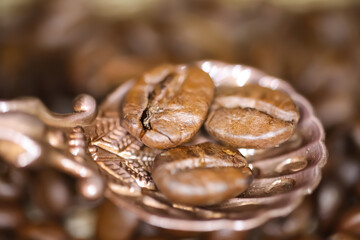 Macro closeup of vintage bronze spoon with three roasted coffee beans, blurred background - obrazy, fototapety, plakaty