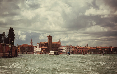 Towers, mansions and lagoon of Venice with riverboats on waves. Ancient italian city with water canals and historical landscape