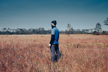 A young man standing poses in the meadow, Rear view , man portrait on landscape , National Park ,Thailand