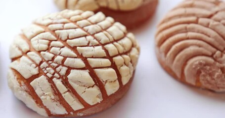Camera going around several Homemade Mexican Conchas. A traditional Mexican sweet bread roll. Round shape and their striped, seashell-like appearance.