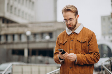 Obraz premium Young handsome man talking on tha phone in winter jacket in the street