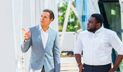 Finance, business and cooperation concept. Two successful businessmen are talking on the street. Office workers are discussing business issues outdoor.