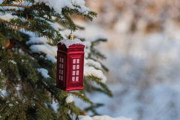Christmas bauble, red telephone box shaped ornament hung on a Christmas tree covered with snow....