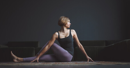 Yoga class. A beautiful, trained body. Woman makes an asana against a dark background in a city...