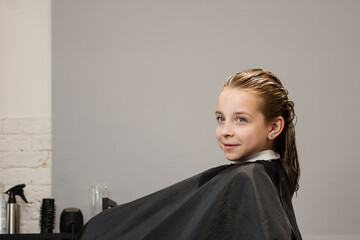 Little girl before the haircut sitting on chair in beauty salon. Children haircuts and hairstyles....