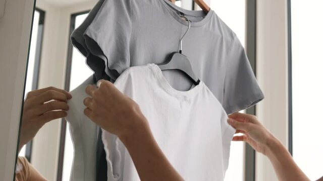 Female hands hanging t-shirts on a hanger. Ironing concept