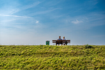 Sitzbank mit P&auml;rchen auf auf einem Landesschutz-Deich auf der Nordseeinsel Juist
