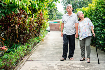 Fototapeta na wymiar Happy senior couple walking together in the garden. Old elderly using a walking stick to help walk balance. Concept of Love and care of the family And health insurance for family