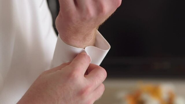 a man fastens a cufflink on his shirt